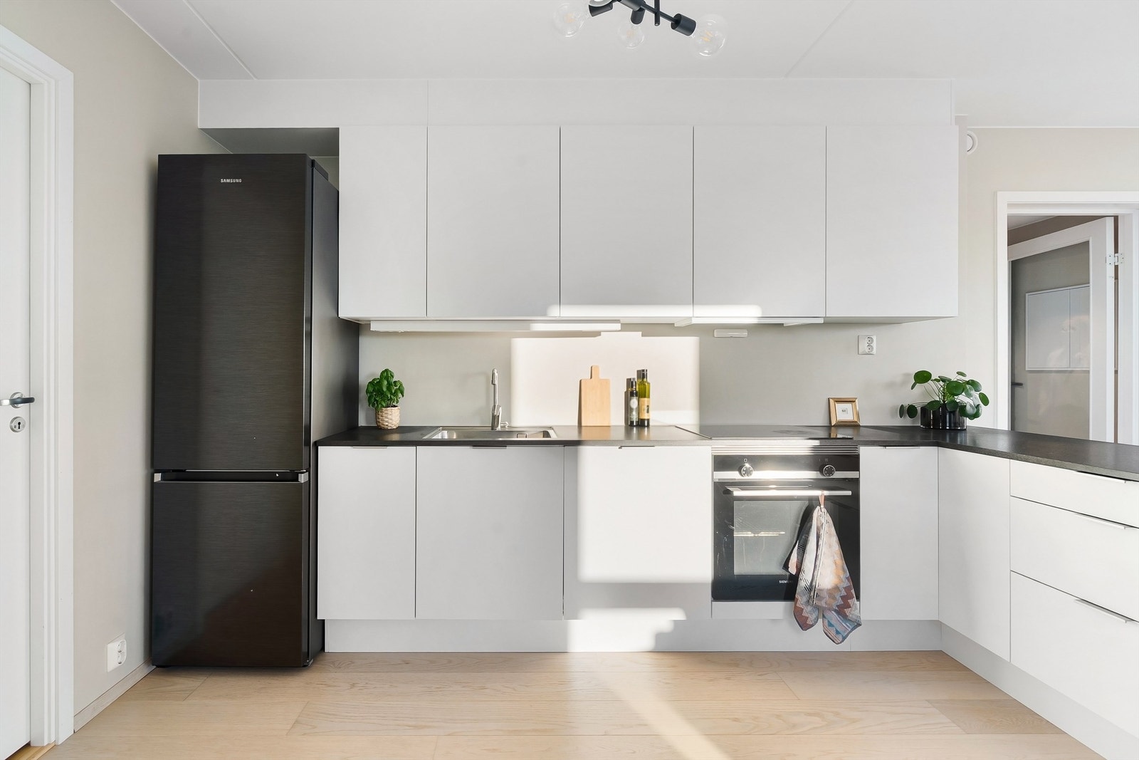 Kjøkkeninnredningen har slette fronter med benkeplate av laminat, oppvaskkum av stål med ett-greps armatur samt belysning og stikkontakter under overskap. Videre er det frittstående kjøleskap med frysedel. Galleribilde