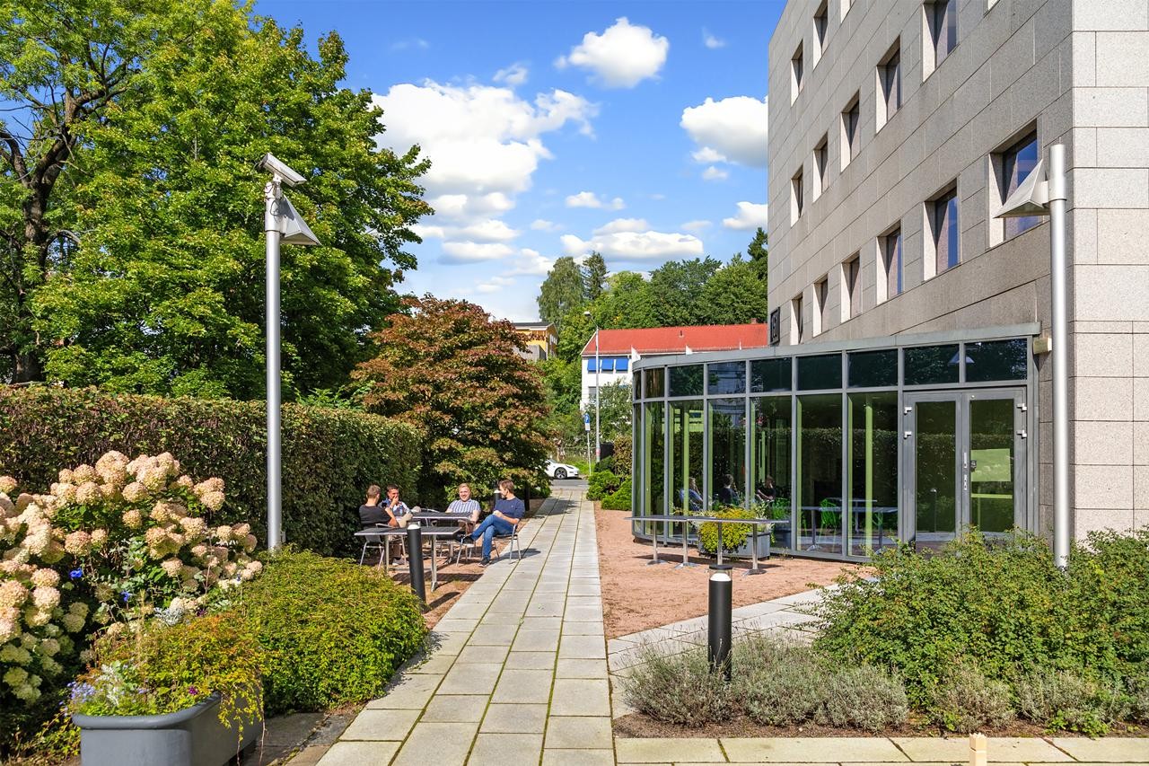 Bakgården er opparbeidet med hyggelige sittegrupper i grønne omgivelser. Galleribilde