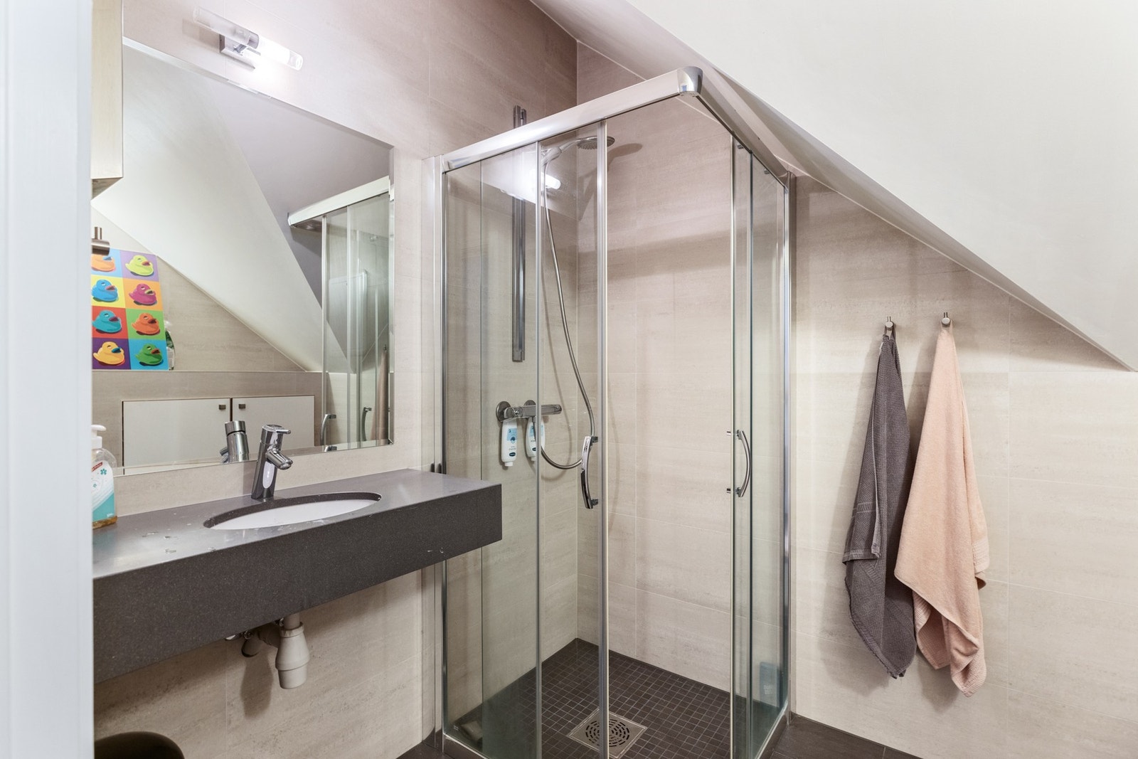 Badet i loftsetasjen er helfliset, og har servantbenk, vegghengt toalett og et dusjhjørne med skyvedører. Galleribilde