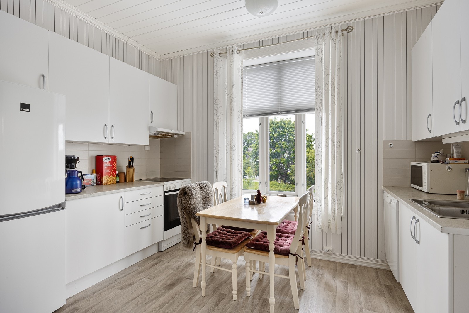 Kjøkken i en leilighet med hvite, glatte fronter og laminert benkeplate. Galleribilde