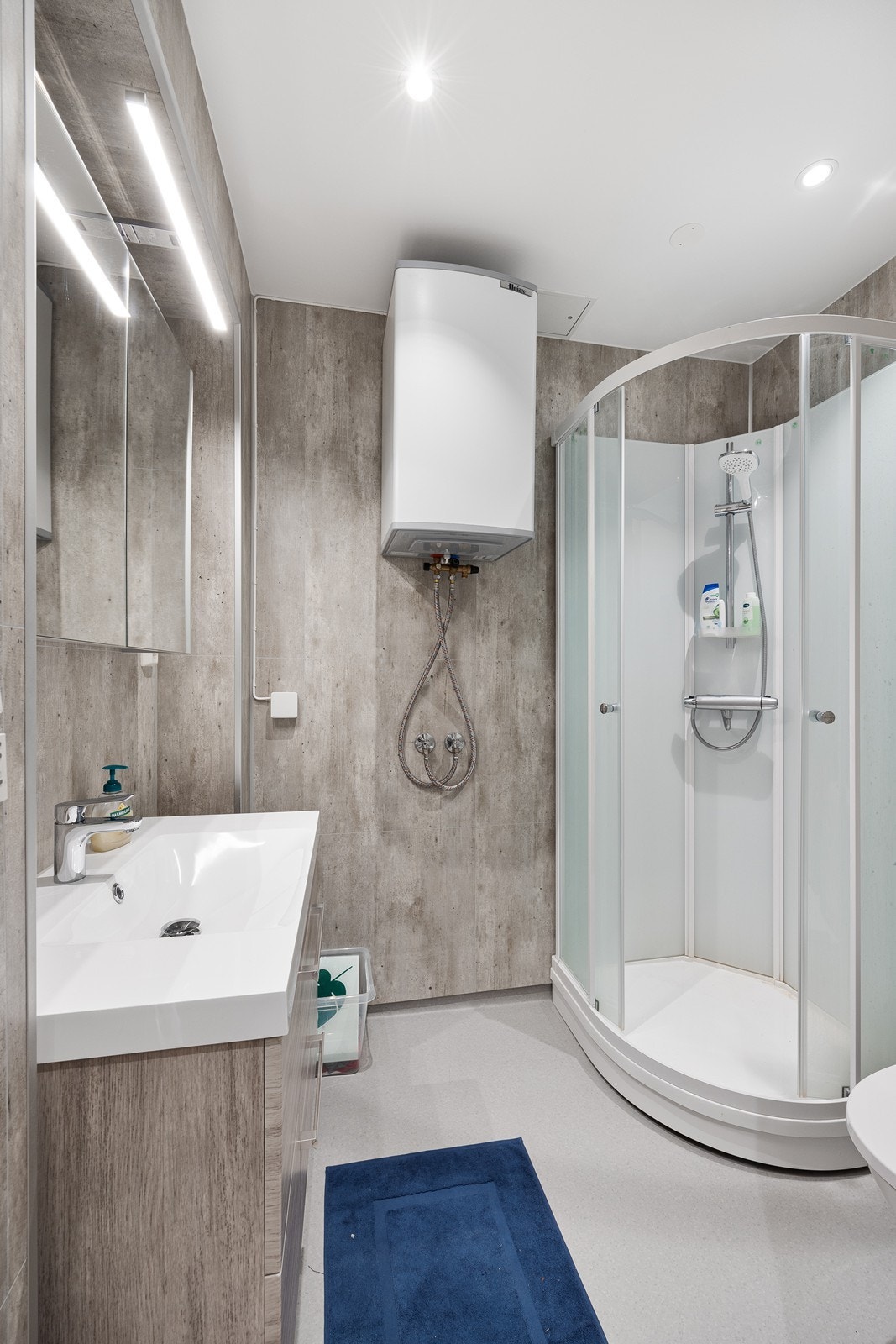 Bad innredet med servant i baderomsinnredning, speil, toalett og dusjkabinett. Galleribilde