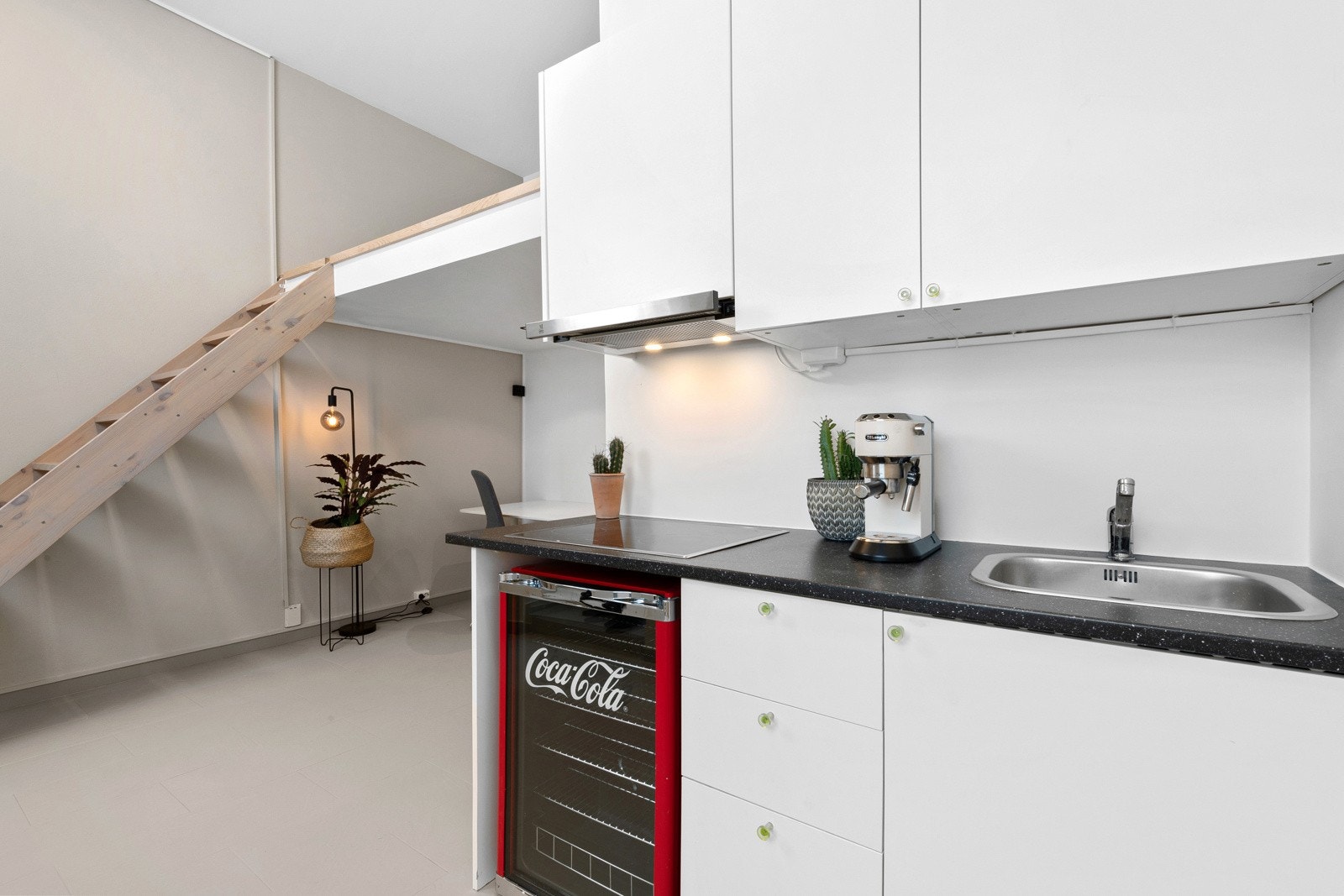 På den ene veggen er det montert en liten Ikea-innredning fra 2013, med hvite, glatte fronter, laminert benkeplate og nedfelt utslagsvask Galleribilde