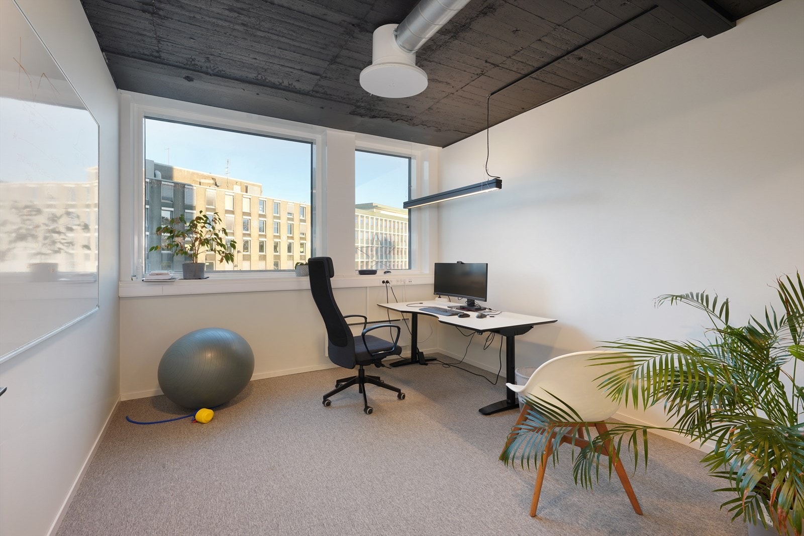 Lys og moderne kontorplass med store vinduer og utsikt mot bymiljøet, ideelt for inspirerende arbeid og produktivitet. Galleribilde