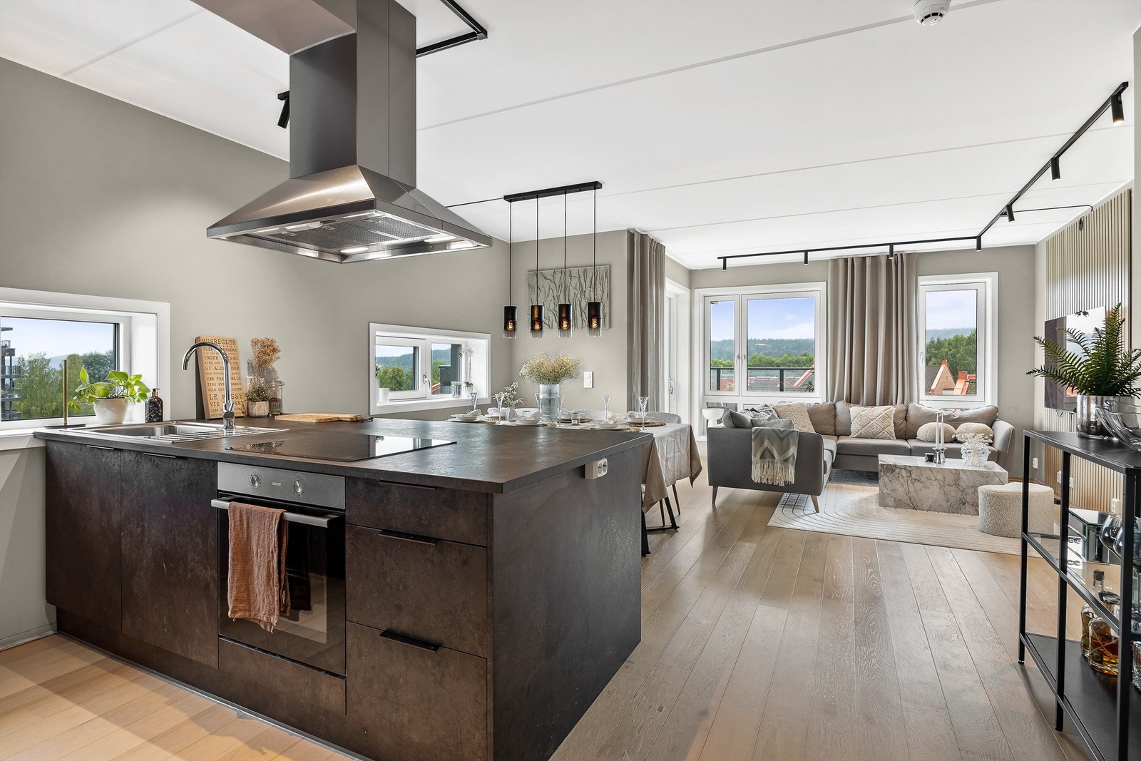 Åpen løsning mellom stue og kjøkken med praktisk kjøkkenøy som har rikelig med oppbevaring. Galleribilde