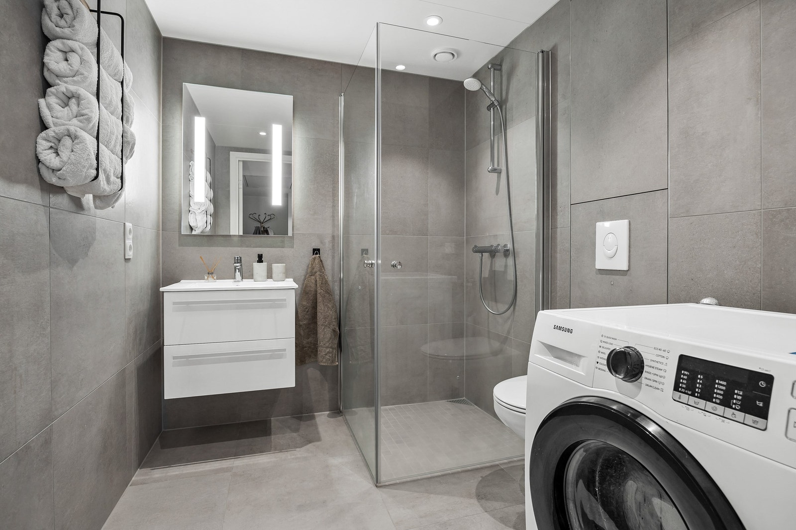 Helfliset bad med varmekabler, dusjhjørne, vegghengt toalett og opplegg for vaskemaskin. Galleribilde