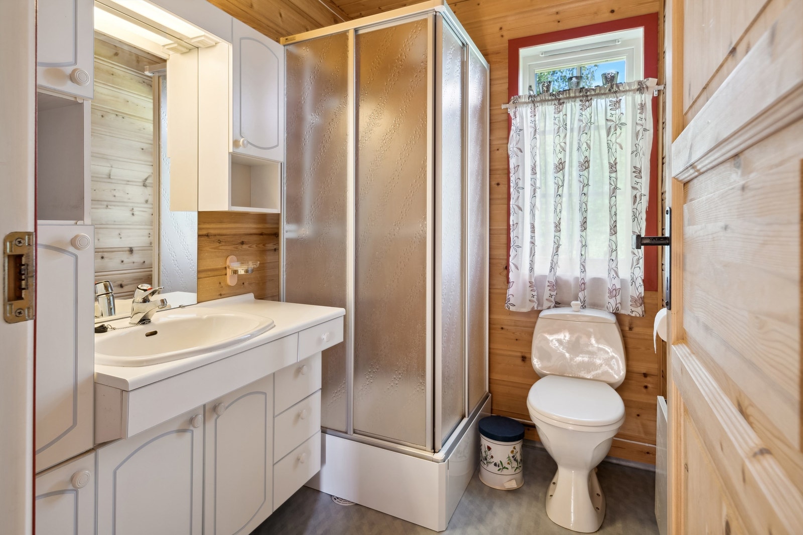 Bad med enkel innredning, dusjkabinett, toalett og servant. Galleribilde