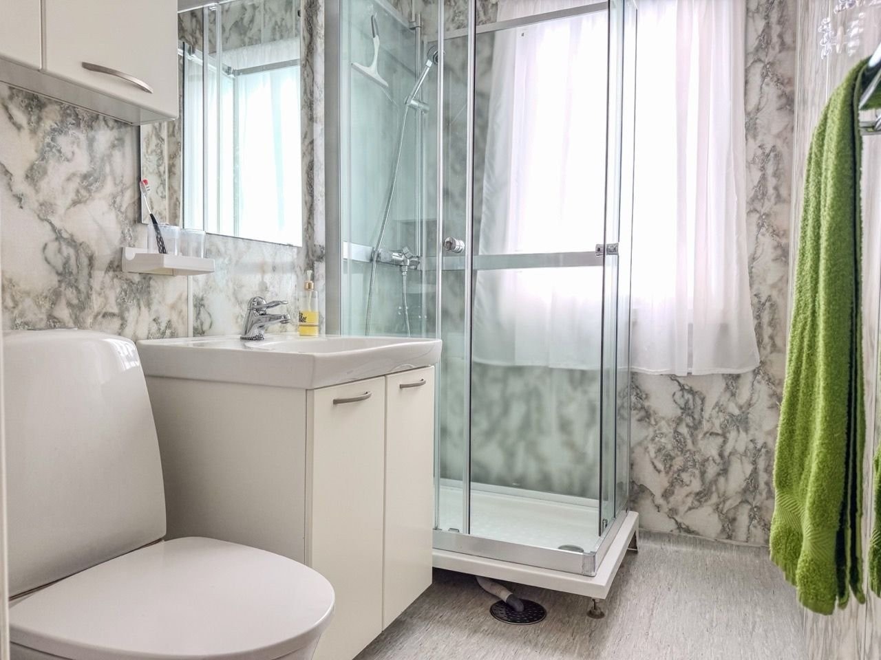 Bad med våtromsplater, dusjkabinett, WC, overskap med speil og servantskap. Galleribilde