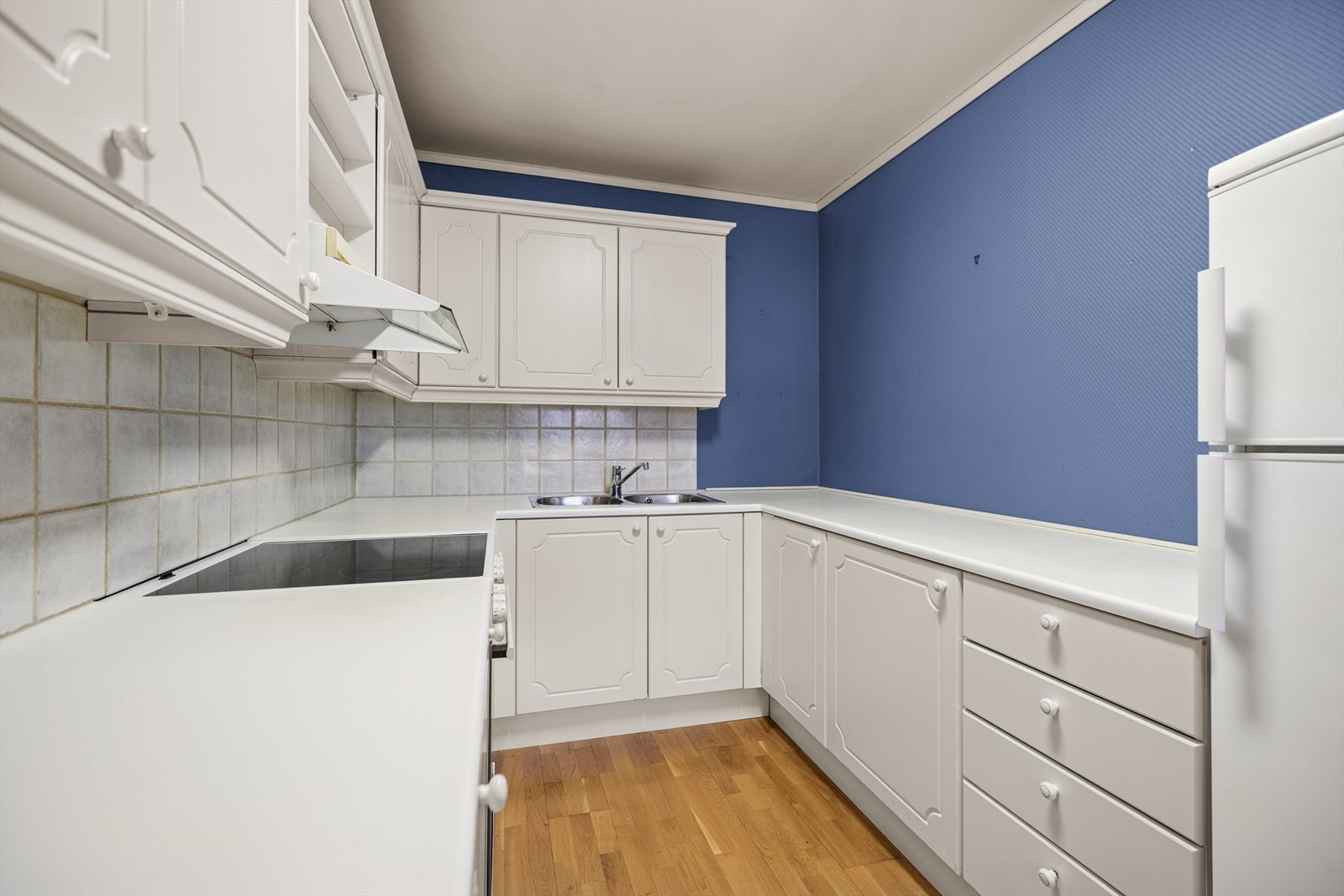 Kjøkkeninnredningen består av hvite, profilerte fronter og en laminat benkeplate med nedfelt stålvask. Galleribilde