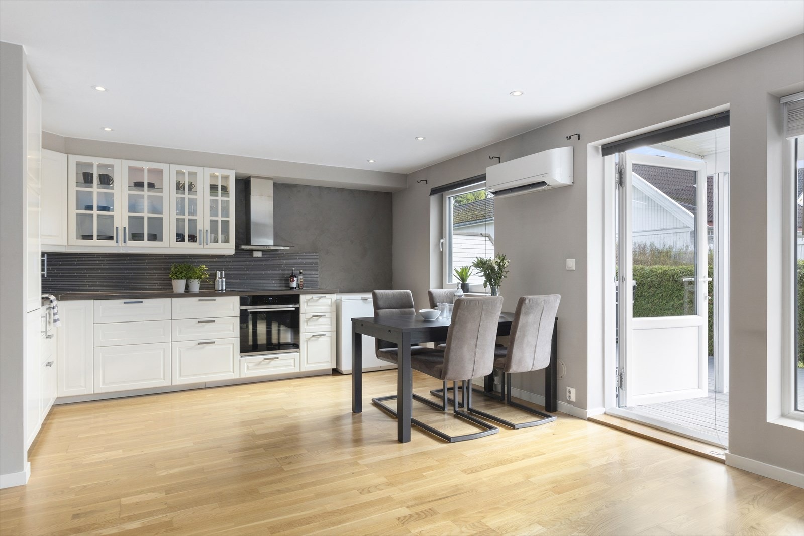 Klassisk kjøkkeninnredning med hvite profilerte fronter og benkeplate av laminat. Kjøkkenet har et moderne preg og har flissatt vegg over kjøkkenbenken og belysning under overskap. Galleribilde