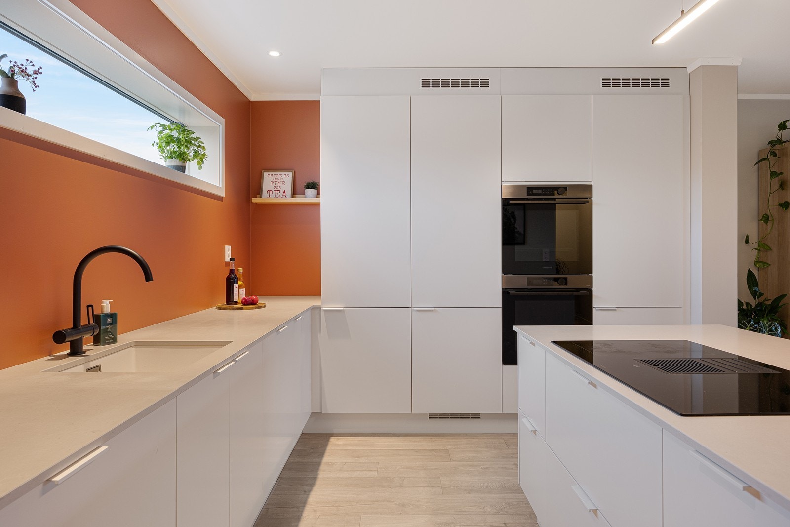 Innredningen er montert langs to vegger og har hvite, slette fronter, lys benkeplater i kompositt og en underlimt komposittkum Galleribilde