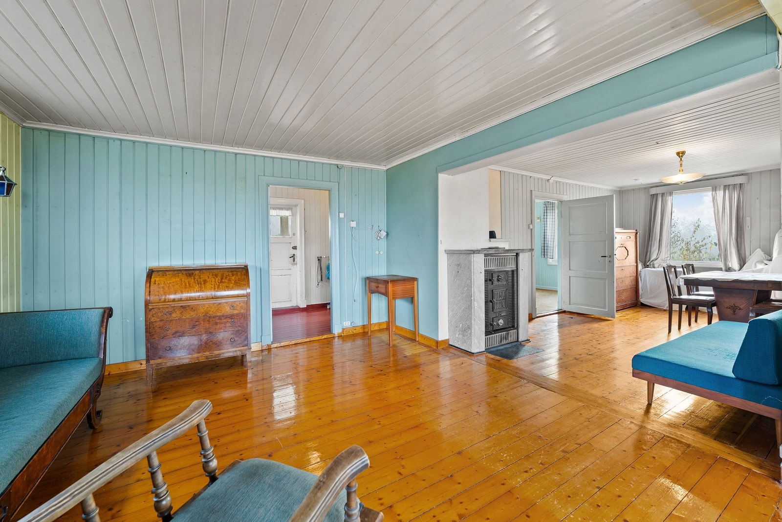Stuen er delt inn i spisestue og sittegruppe, med eldre tregulv og malt panel. Galleribilde