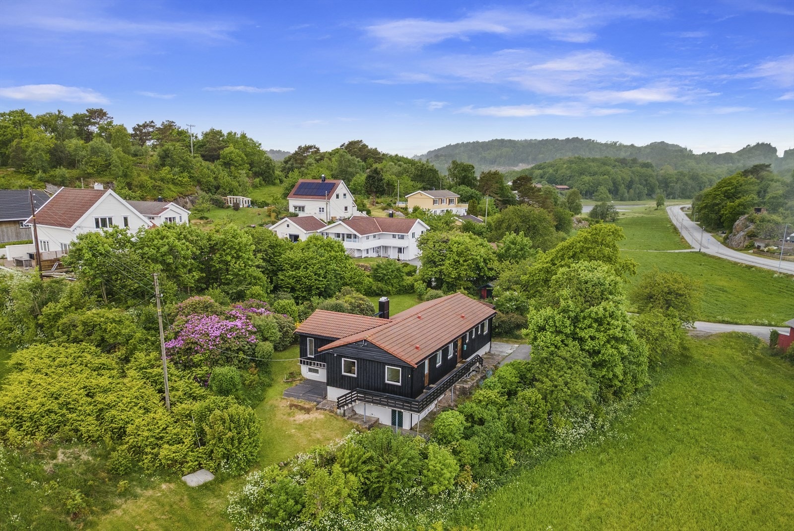 Boligen ligger på en stor tomt som er pent opparbeidet med plen, prydbusker og flere opparbeidede sittesteder Galleribilde