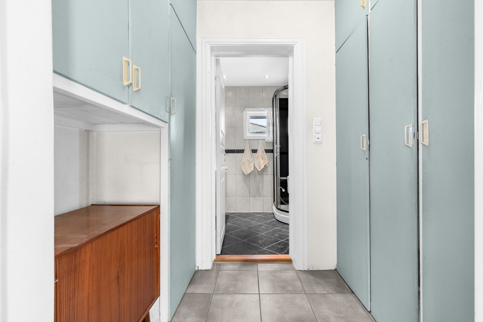 Fra stuen i 1. etasje er det adkomst til en mellomgang med god oppbevaringsplass i flere plassbygde garderobeskap. Fra gangen er det adkomst til baderommet. Galleribilde