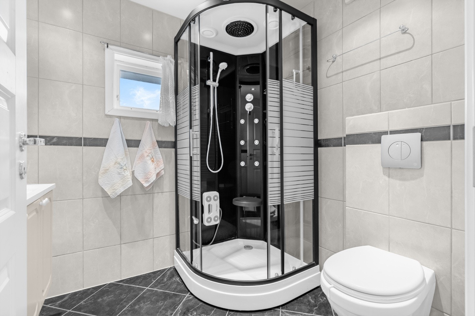 Baderommet er også utstyrt med dusjkabinett med regnfallsdusj og steamfunksjon, samt vegghengt toalett. Galleribilde