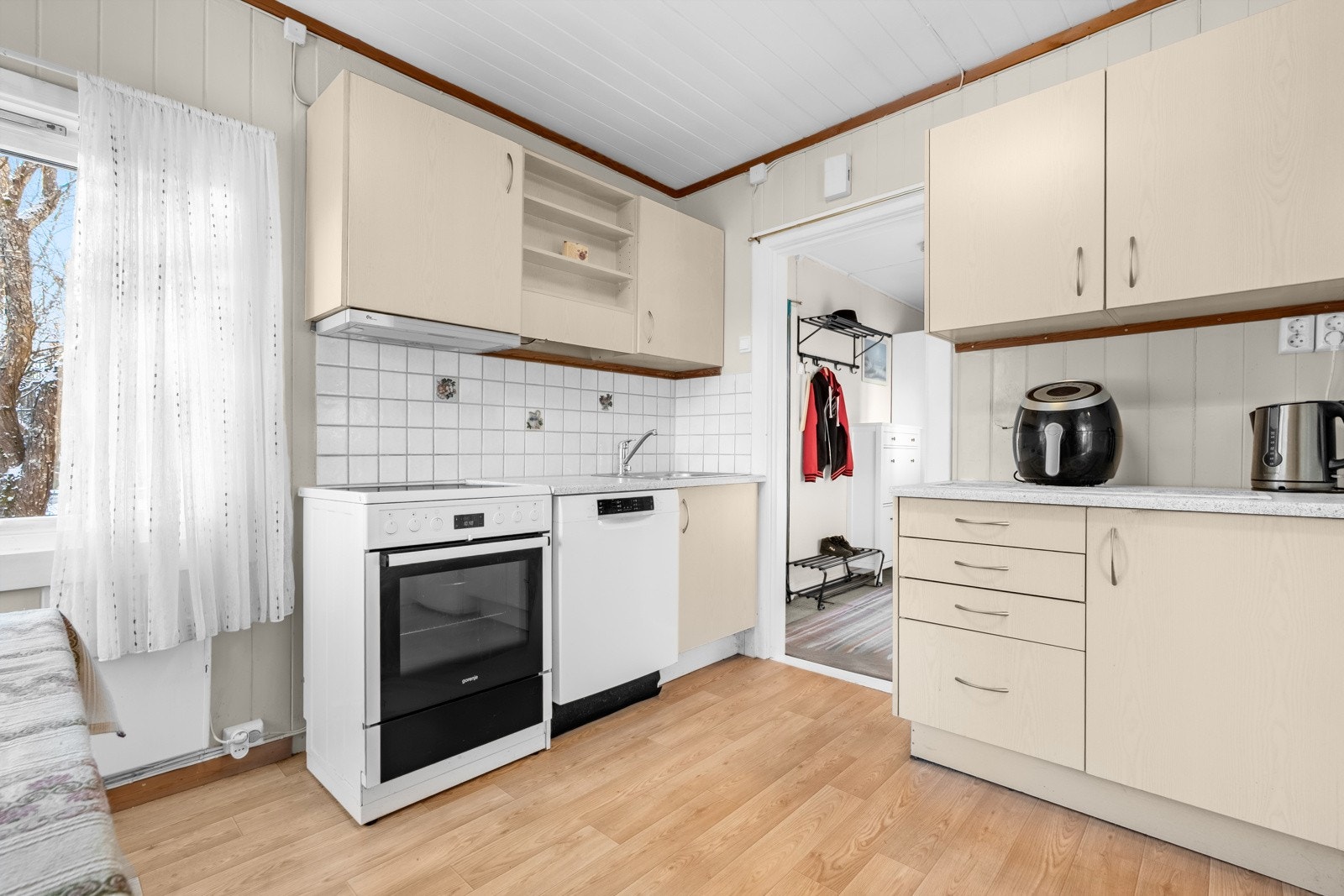 Kjøkkeninnredning fra 2002 med glatte fronter, laminert benkeplate med nedfelt oppvaskkum og fliser i benkeryggen ved platetoppen og kummen. Galleribilde