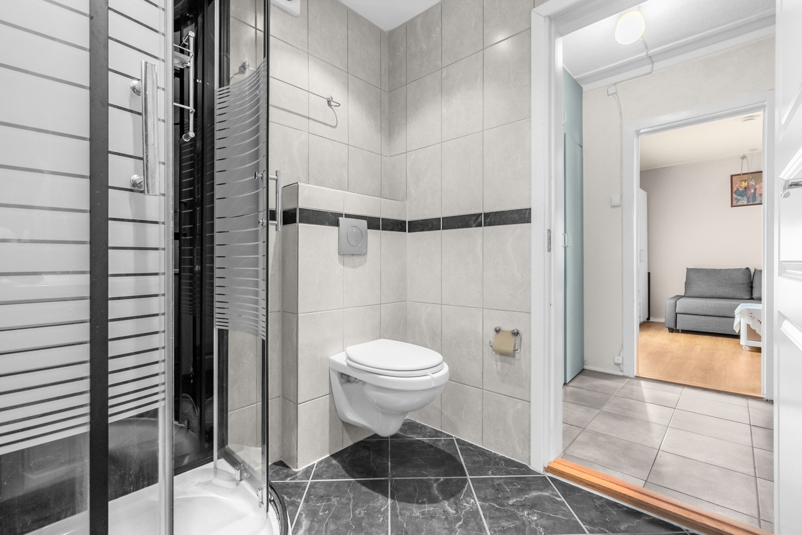 Baderommet har mørke fliser på gulv med gulvvarme, lyse fliser på veggene, downlights i himlingen og mekanisk avtrekksvifte. Galleribilde