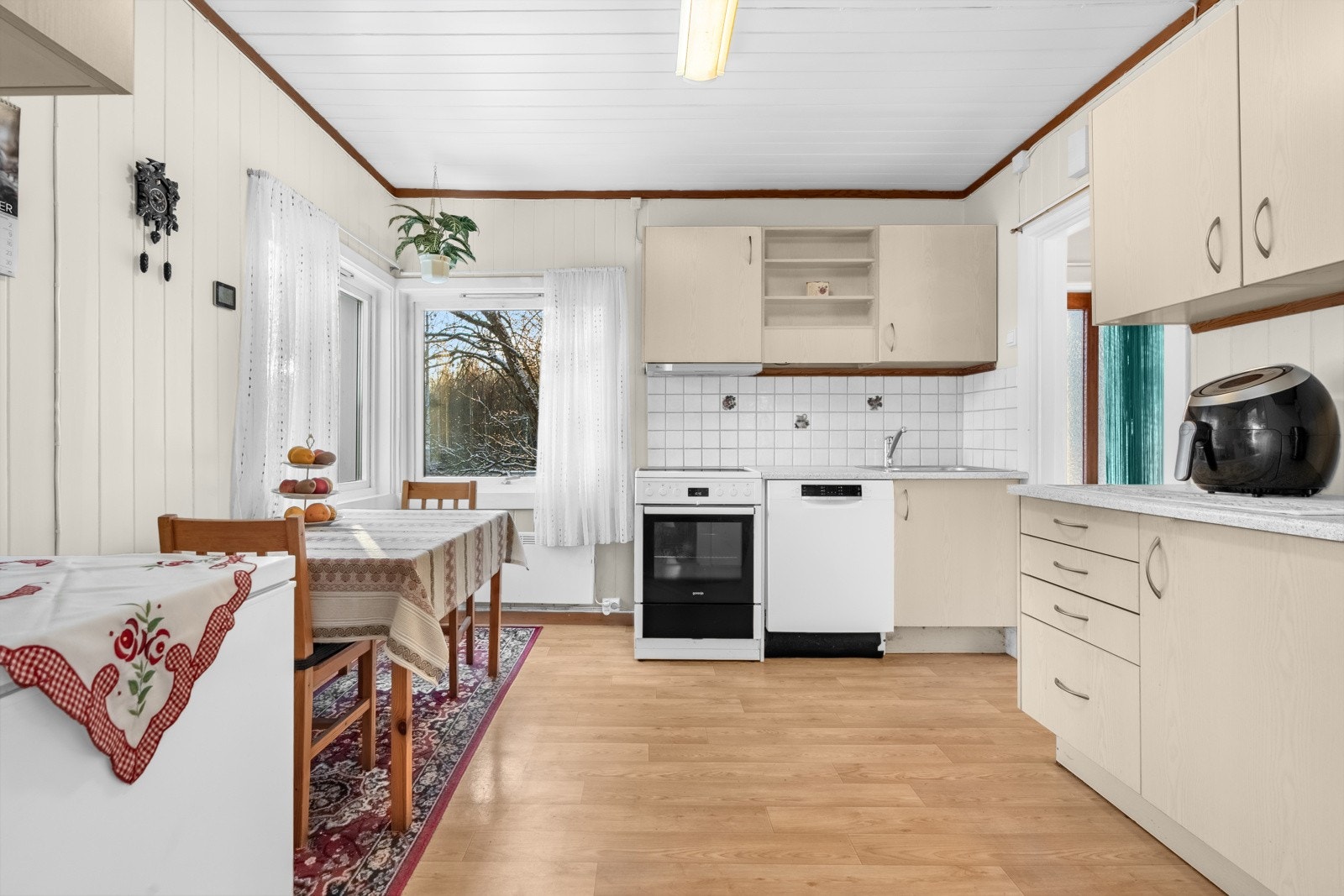 Kjøkkenet har enstavs laminat på gulv, lysmalte overflater og hjørnevindu som slipper inn naturlig lys. Galleribilde