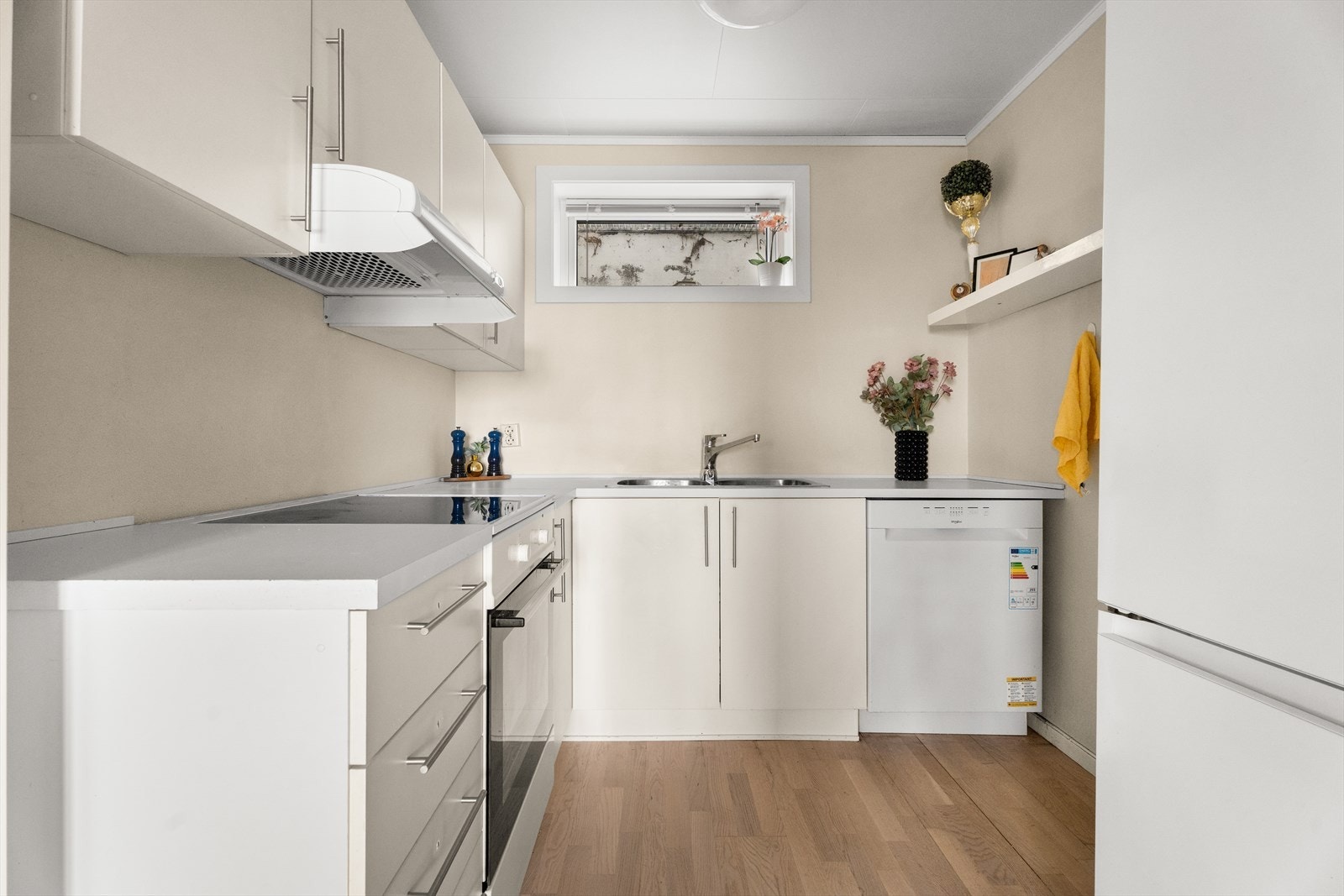 Klassisk kjøkken med glatte fronter og en laminert benkeplate med nedfelt oppvaskkum i stål Galleribilde