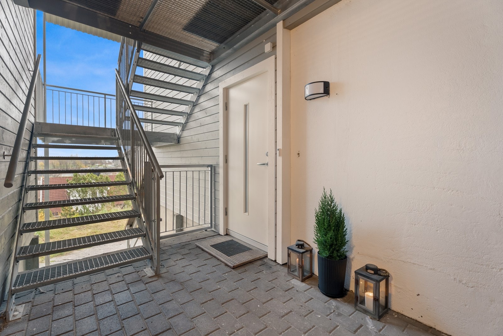 Malt inngangsdør med glassfelt gir lys til inngangspartiet, som har steinbelagt adkomst Galleribilde