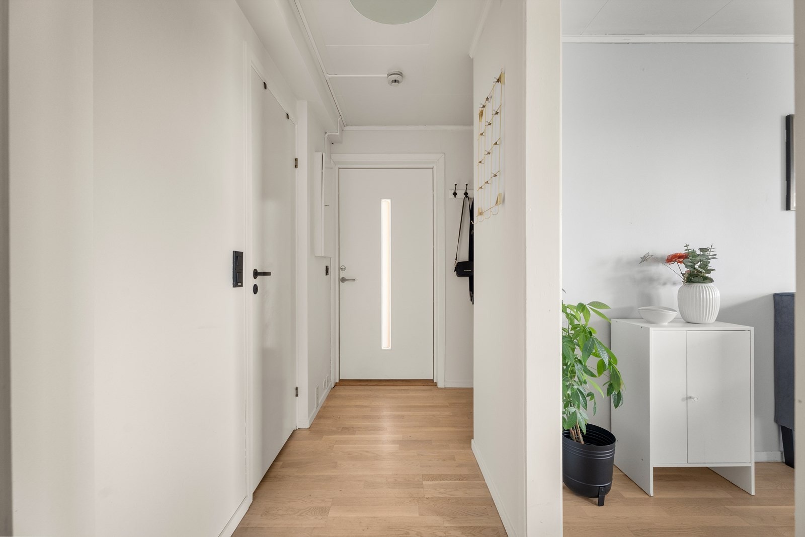 Trivelig entré med parkettgulv og lyse vegger. Her finnes en praktisk garderobeløsning med knagger og hattehylle, samt plass til yttertøy og sko Galleribilde