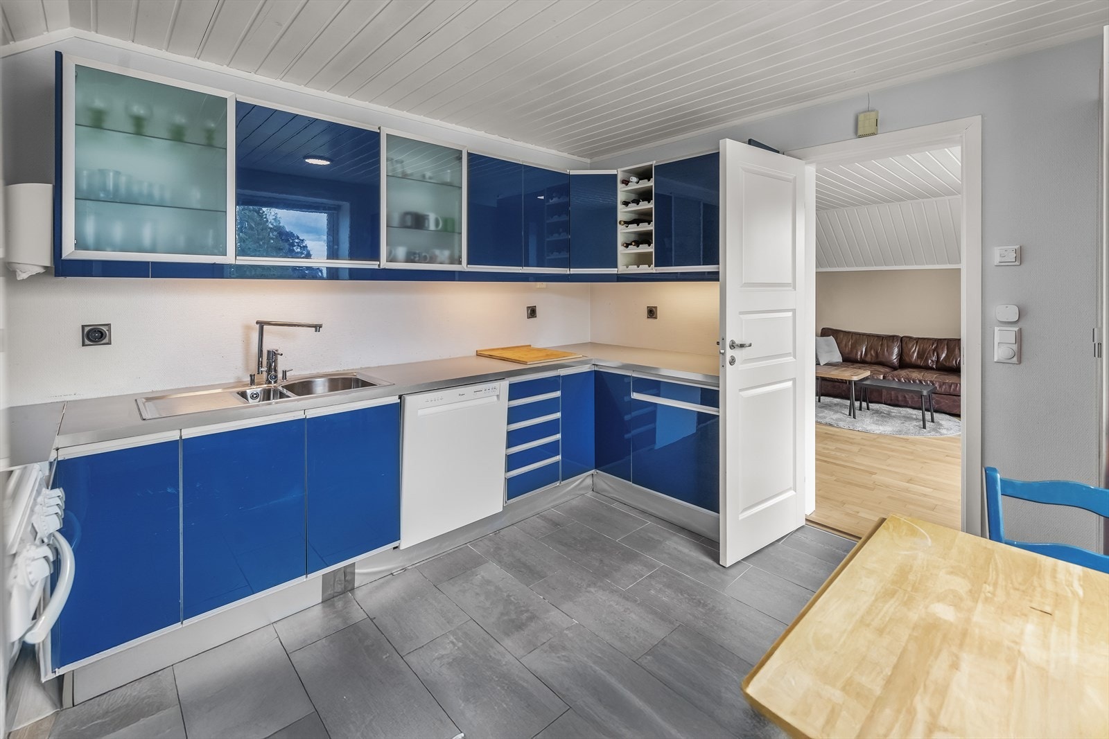 Kjøkkenet er fint plassert i egen sone og praktisk utformet med slette fronter og benkeplater i laminat med fliser over. Galleribilde