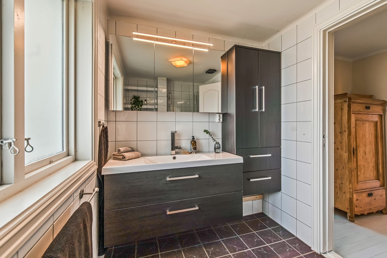 Baderomsinnredningen har finerte fronter og består av en heldekkende servant på en skuffeseksjon, et høyskap og et bredt speilskap med belysning. Galleribilde