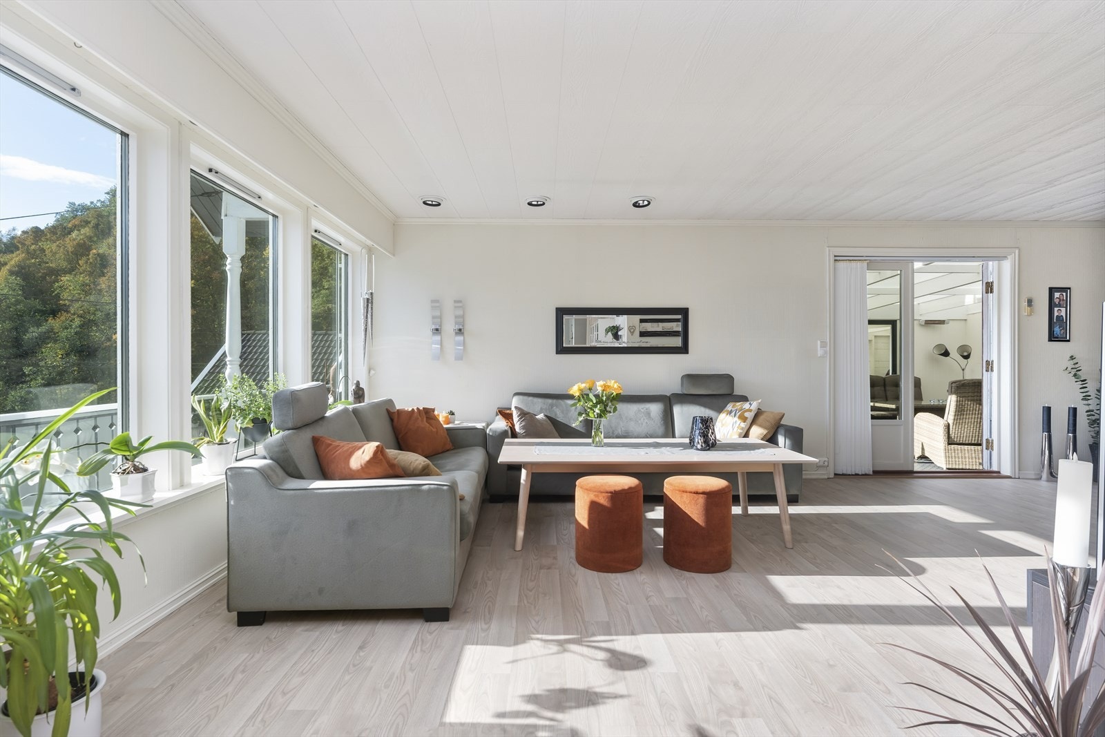 Stuen har store vindusflater som gir rikelig med naturlig lys og utsikt mot det grønne landskapet. Galleribilde