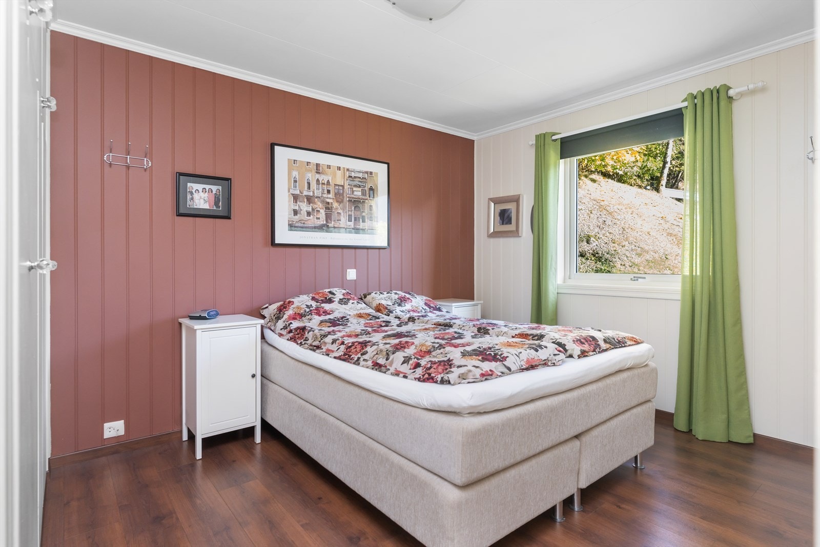 Soverommet har en kontrastvegg med panel og laminatgulv, samt vindu med utsikt til hagen. Galleribilde