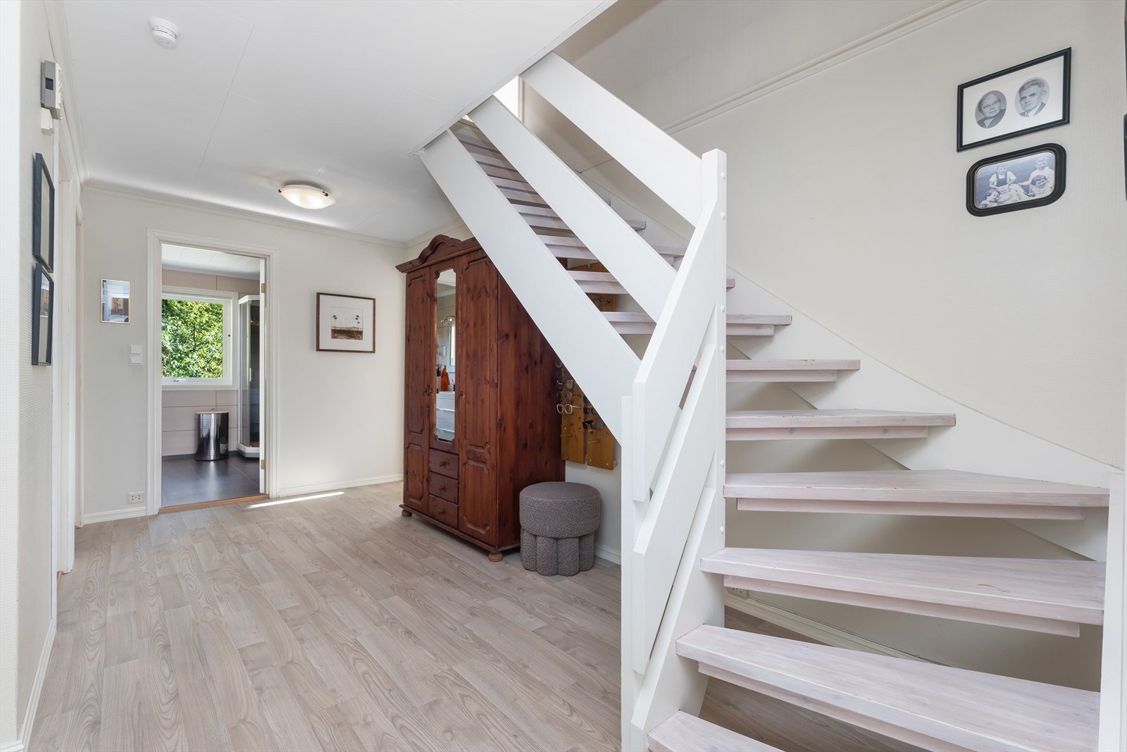 Lys trappegang som leder til stue med store vinduer i front. Galleribilde