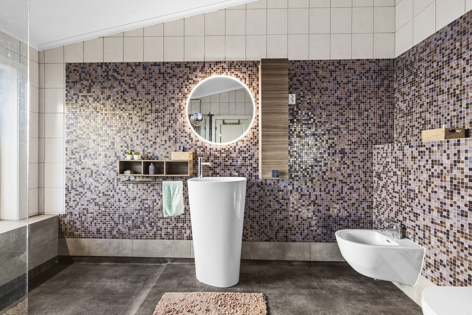 Baderommet er nyoppusset med moderne og stilrene mosaikkfliser, en stor og åpen dusjsone, frittstående servant og vegghengt toalett. Galleribilde