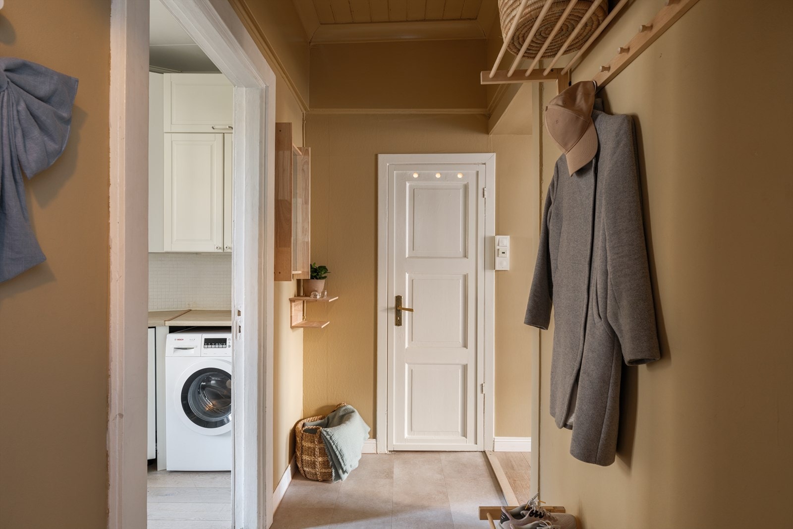 En flott entré malt i en delikat gulfarge, som gir et godt førsteinntrykk av leiligheten Galleribilde