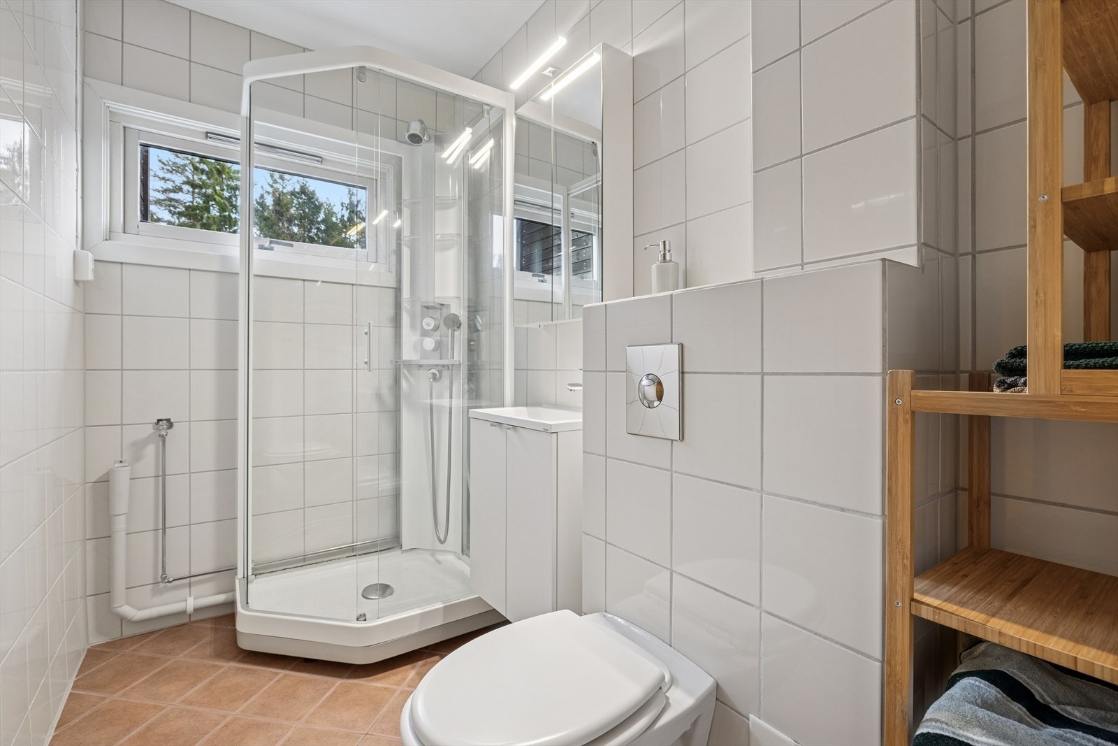 Flislagte vegger og gulv med gulvvarme gir et komfortabelt bad. Dusjkabinett og opplegg for smal vaskemaskin. Galleribilde