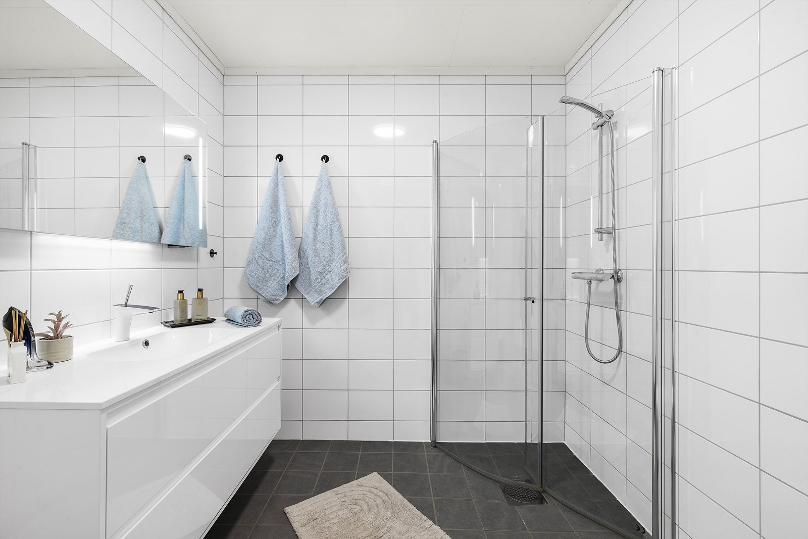 Baderommet i denne etasjen har flislagt på gulv med varmekabler. Det inneholder vegghengt toalett, innredning med servant og dusjhjørne med innsvingbare dører. Galleribilde