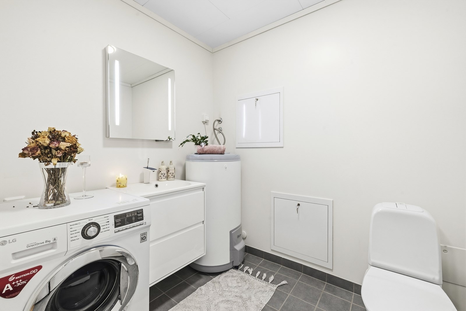 Kombinert toalett/vaskerom i 1. etasje med flislagt gulv med varmekabler og platede/malte vegger. Galleribilde