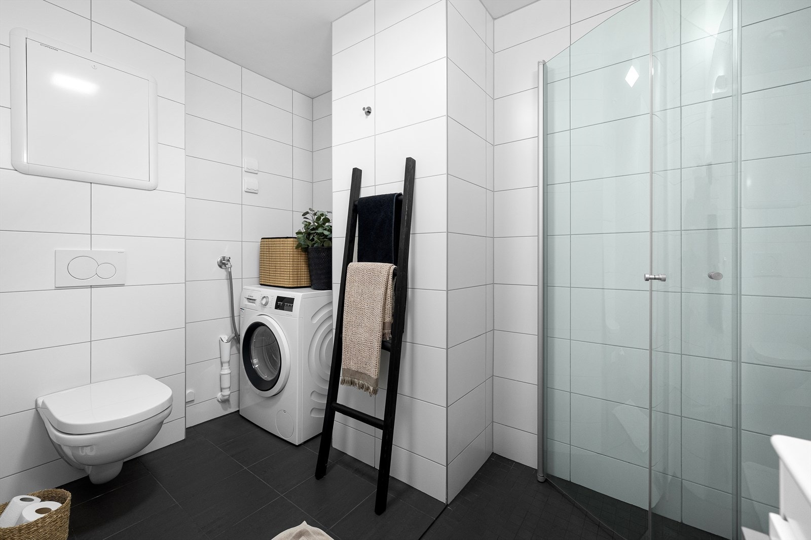 Badet er innredet med vegghengt toalett og en moderne baderomsinnredning med speilskap. Dusjhjørne med innfellbare glassdører Galleribilde