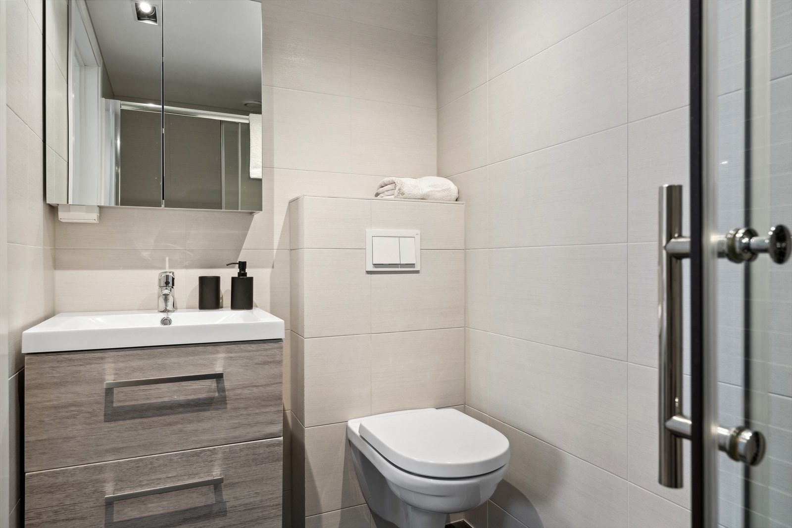 Delikat, flislagt dusjbad med innredning, dusj med skyvedører og vegghengt WC. Badet ligger i tilknytning til hovedsoverommet. Galleribilde