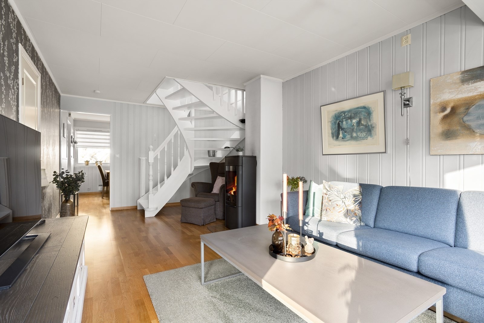 Ved vinduene er det plass til hjørnesofa og tv-benk, og nærmest kjøkkenet er det peisovn og trapp opp til loftsetasjen. Galleribilde