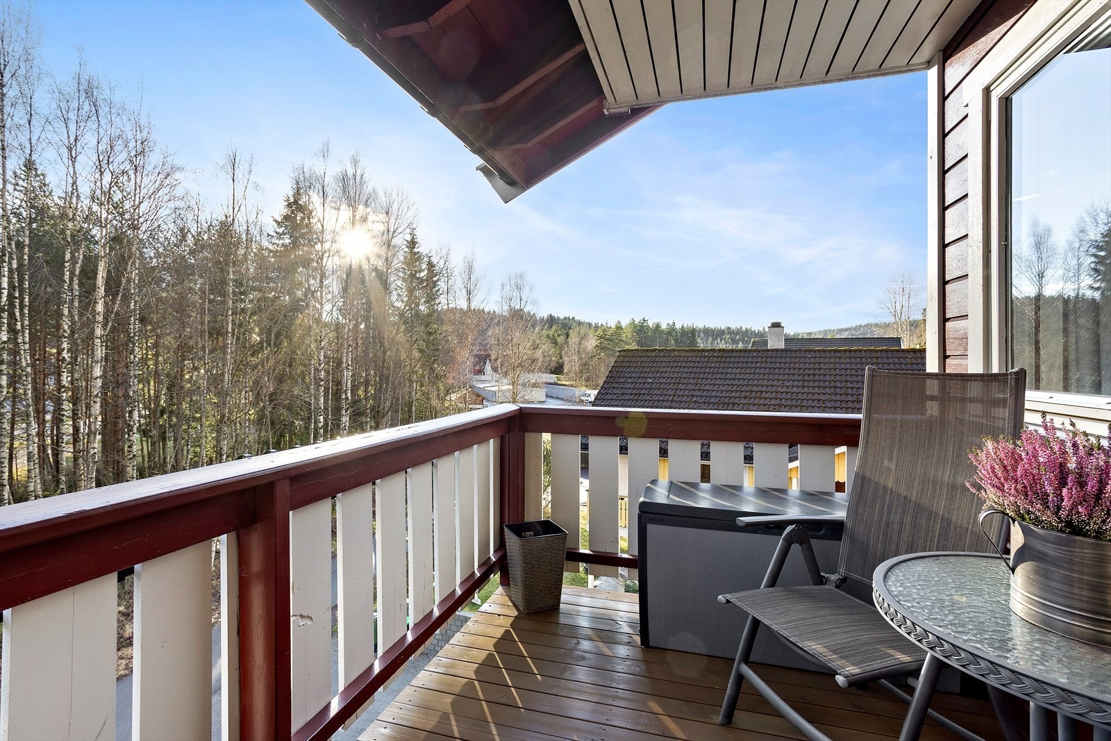 Overbygd balkong med nydelig utsikt mot vakker natur. Balkongen har spaltegulv av tre, rekkverk med stående panel og god plass til to komfortable stoler. Galleribilde