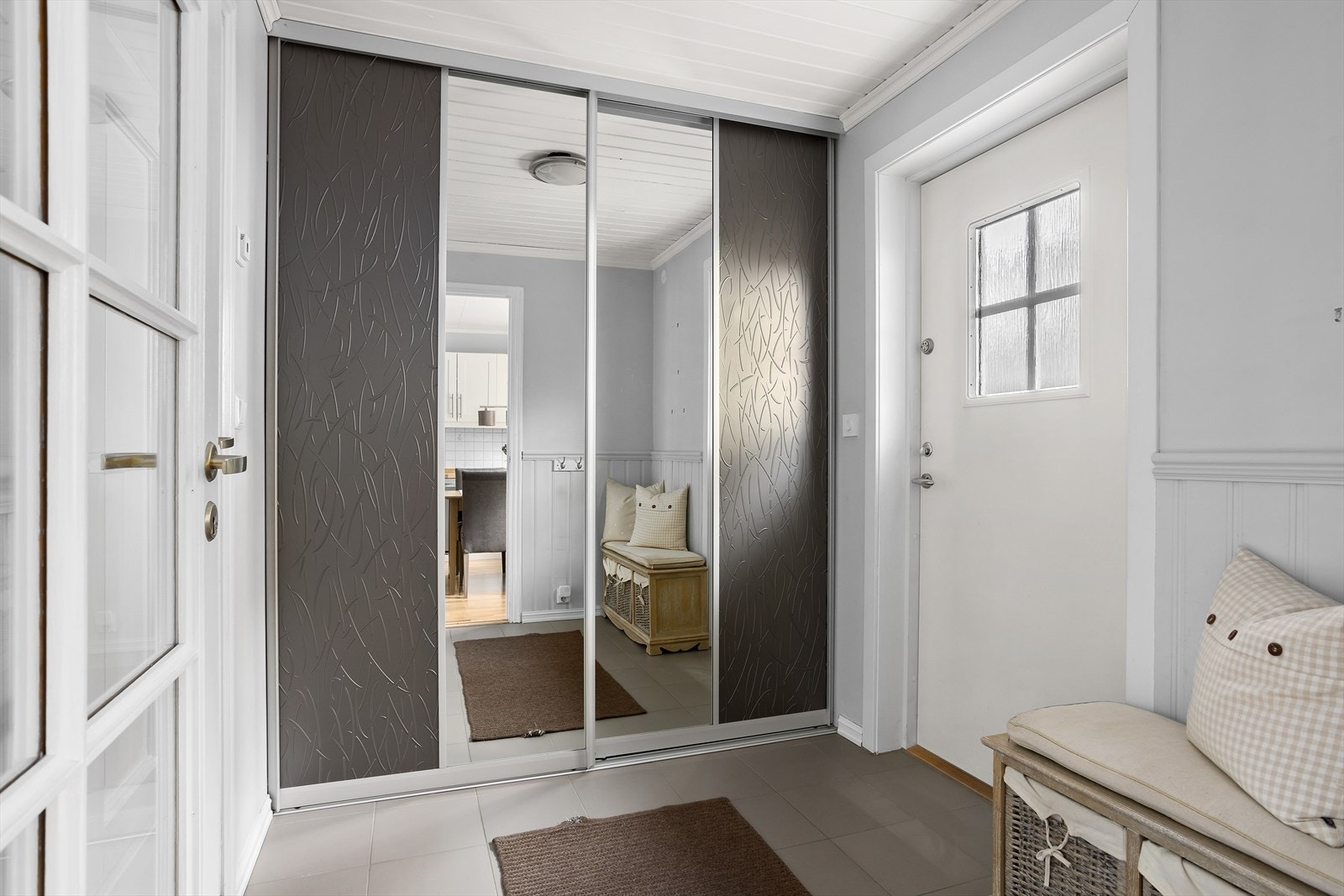I entreen er det grå fliser med gulvvarme og gråmalte vegger med brystning på nedre del. Den ene veggen er dekket med skyvedørsgarderobe. Galleribilde