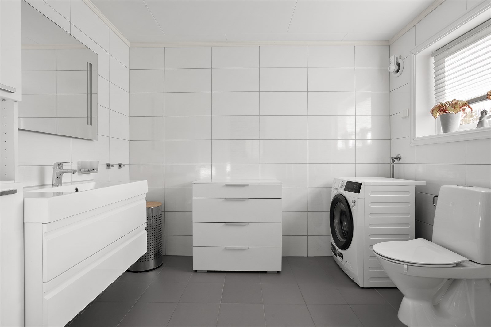 Stilen er klassisk, med store, hvite fliser på veggene og grå fliser over gulvvarme. Galleribilde