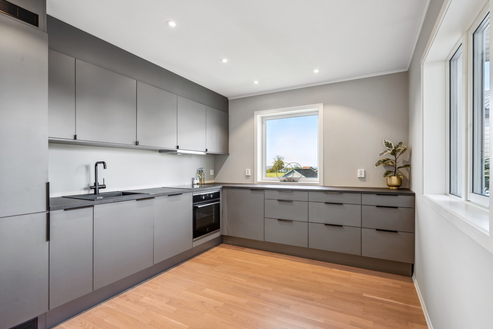 Stilren innredning i glatte fronter, benkeplater av laminat og integrerte hvitevarer Galleribilde