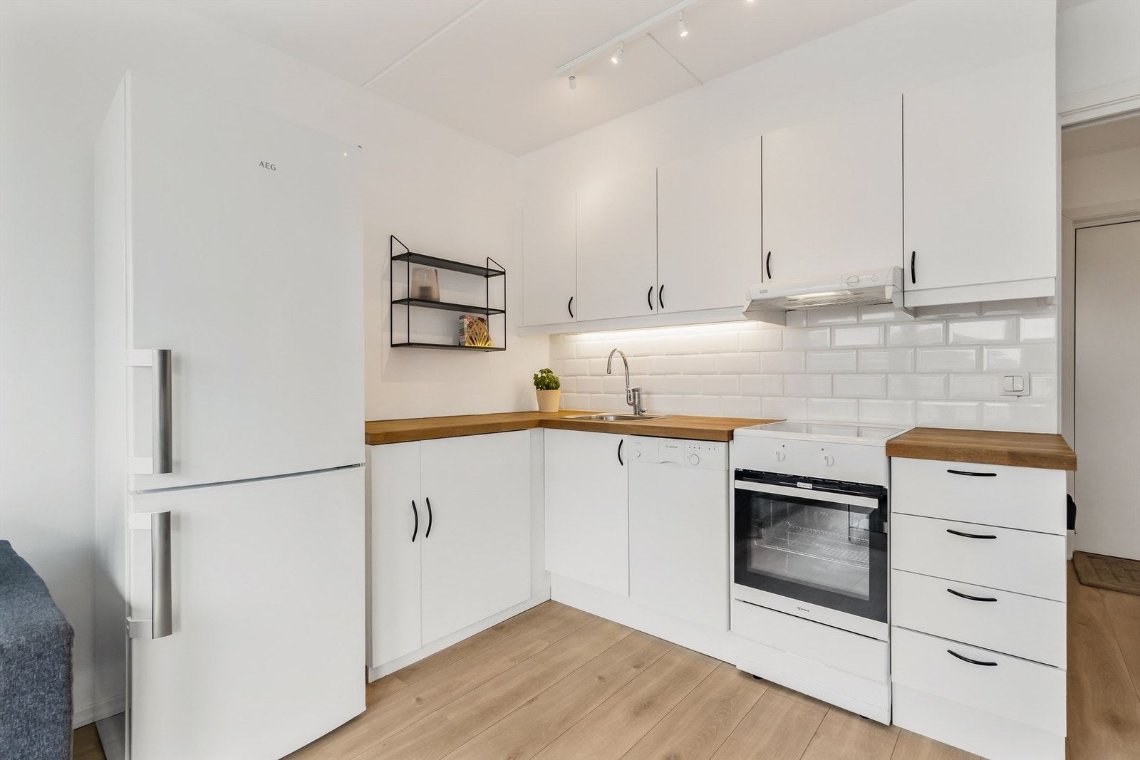 Pen kjøkkeninnredning med over- og underskap i hvit samt glatt utførelse Galleribilde