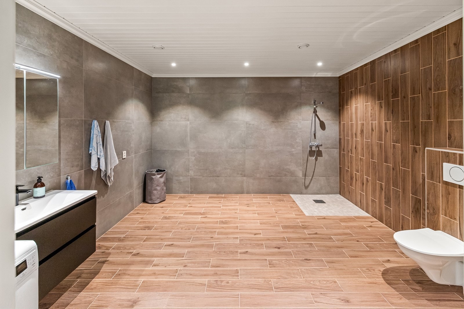 Stort og romslig baderom nr. to med vegghengt toalett, dusjhjørne, servant og opplegg til vaskemaskin. Galleribilde