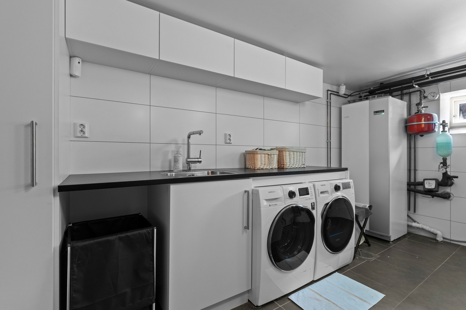 Vaskerom fra 2011. Vaskerommet fungerer også som teknisk rom med installasjoner tilknyttet varme anlegget i boligen. Opplegg for vaskemaskin og tørketrommel samt utslagskum. Galleribilde