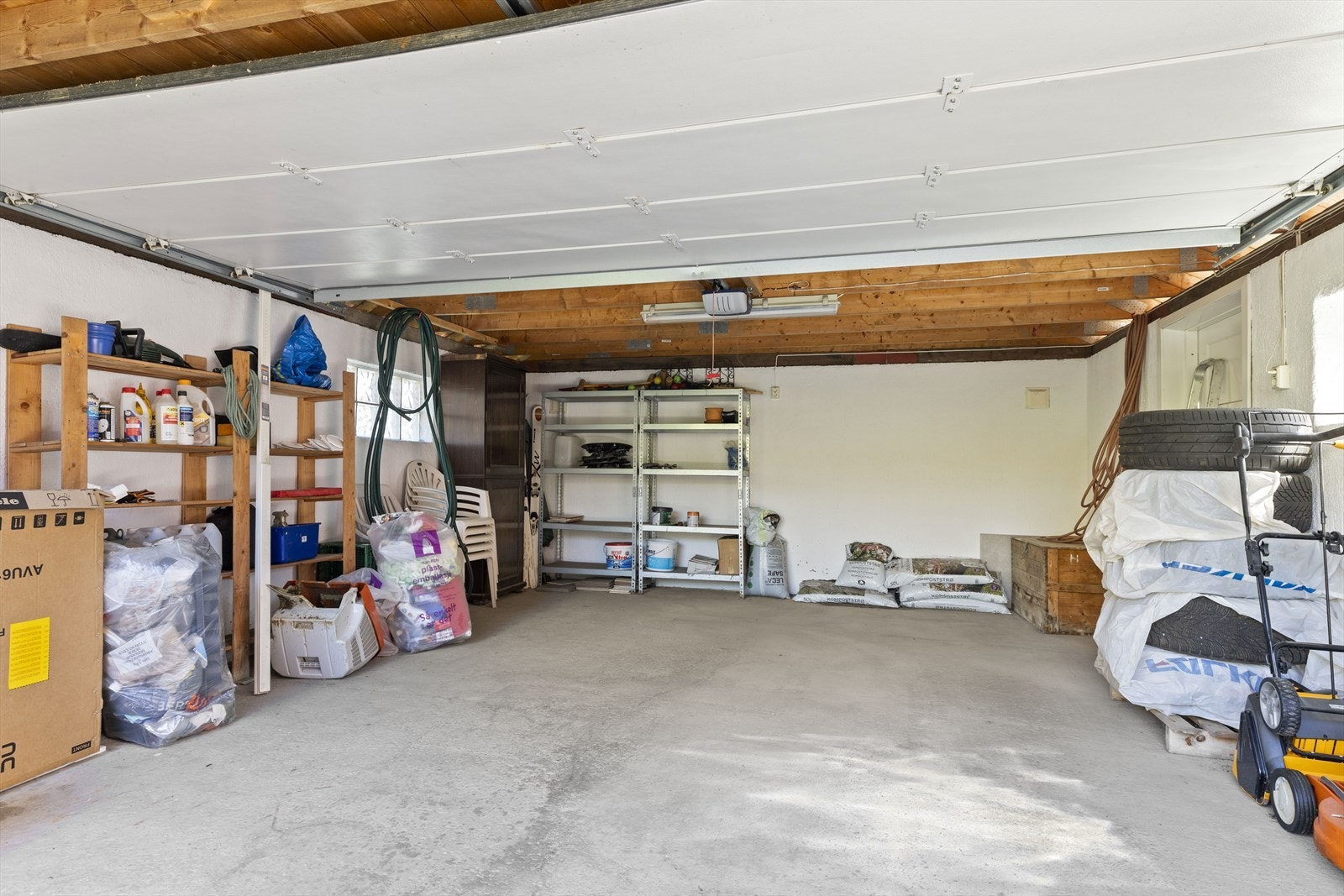 Frittstående dobbeltgarasje i enden av nedkjørsel. Det montert Tesla-lader i garasjen Galleribilde