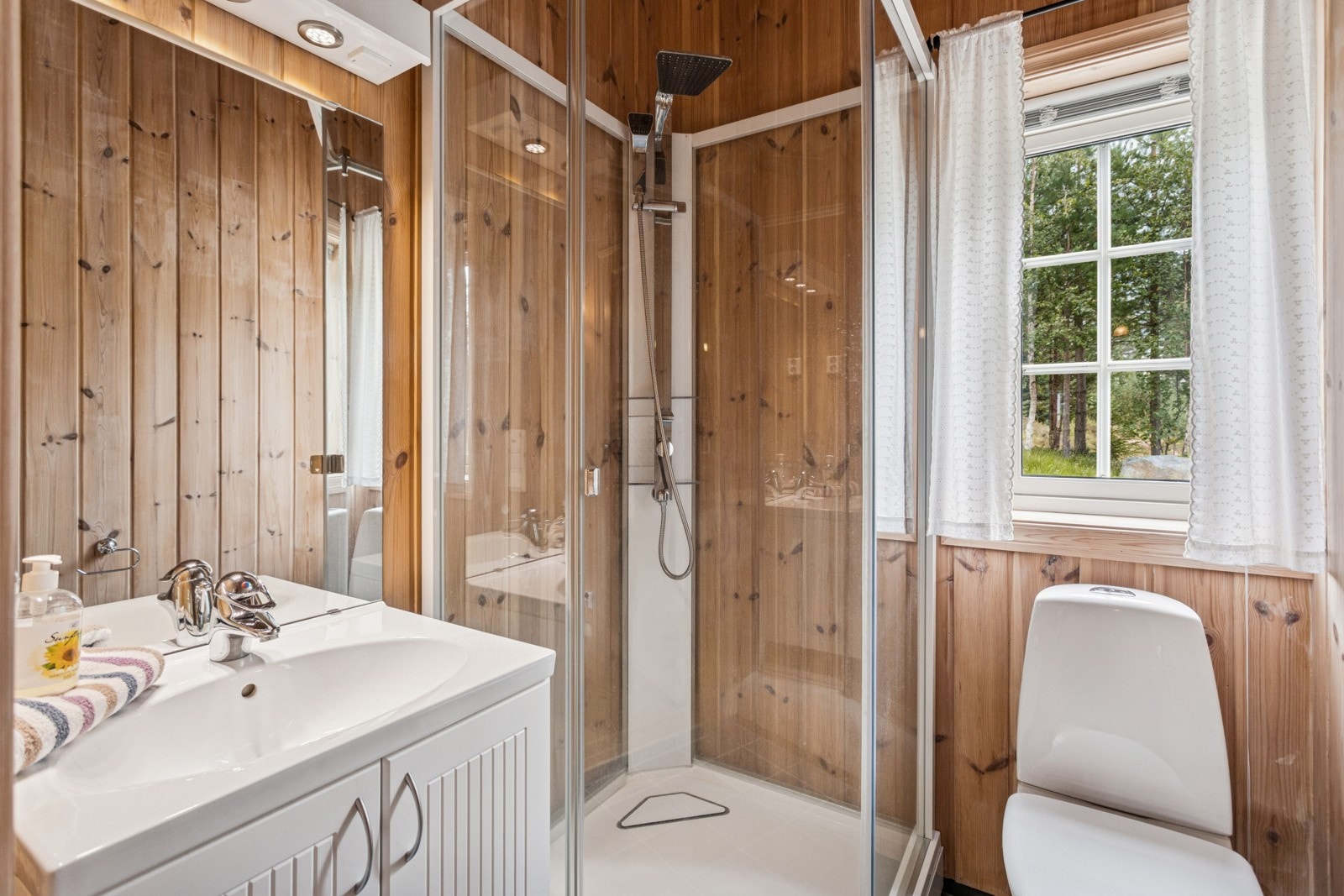 Baderom med adkomst fra gang. Her er det flislagt gulv og vegger med panel. På badet finner du toalett, dusjkabinett og baderomsinnredning med nedfelt servant og speil på vegg. Varmekabler i gulvet. Galleribilde