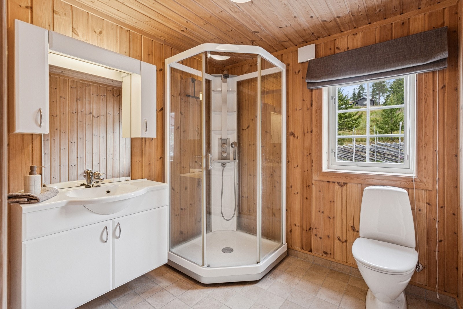 Baderom i 1.etasje med flislagt gulv og vegger med panel. Her finner du toalett, dusjkabinett og baderomsinnredning med nedfelt servant og speil med belysning over. Varmekabler i gulvet. Galleribilde