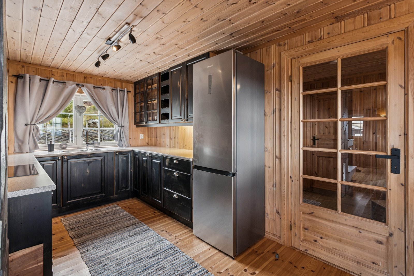 På kjøkkenet finner du en mørkmalt innredning med profilerte fronter i heltre. Innredningen har takhøye overskap og flere overskap med vitrinefronter, samt egen vinhylle. Galleribilde