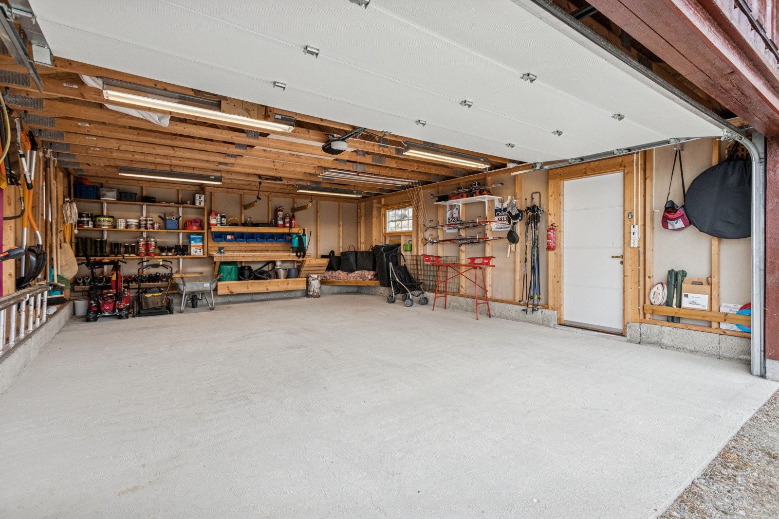 Dobbelgarasje. Garasjen er innredet med flere hyller, arbeidsbenk mm. Galleribilde