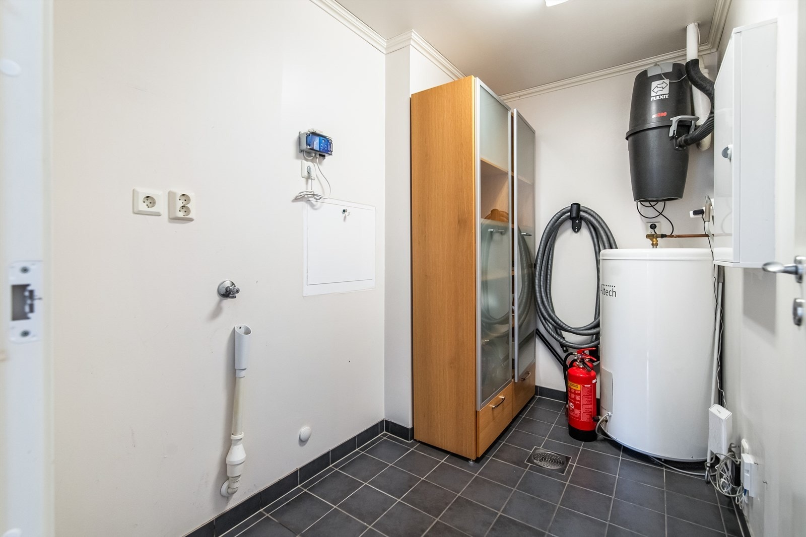 Vegg i vegg med baderommet er det et separat og praktisk vaskerom med opplegg til vaskemaskin. Her er også boligens varmtvannsbereder plassert og sikringsskap. Galleribilde